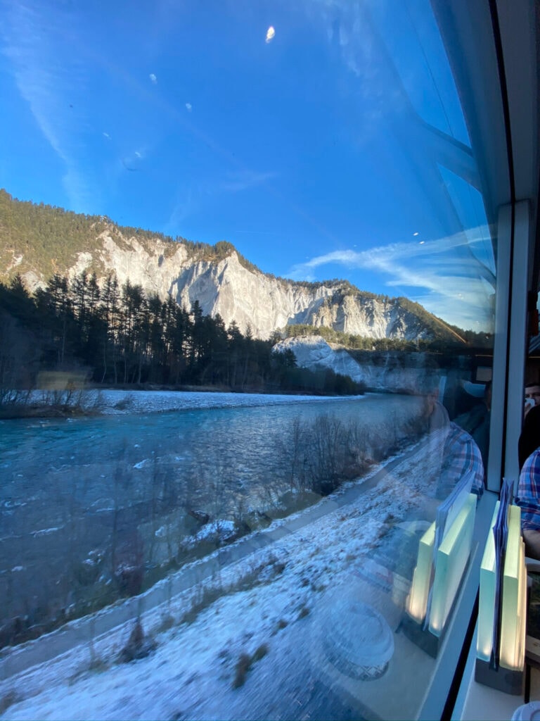 Foto aus dem Zug mit Ausblick auf blauen Himmel und Berge