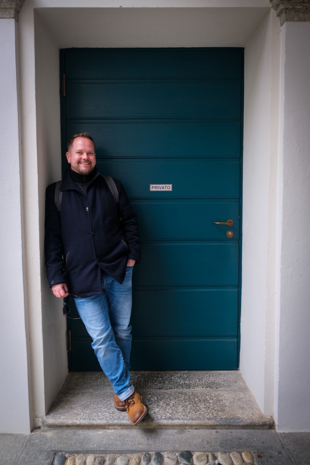 Velthy leaning against a large turquoise door