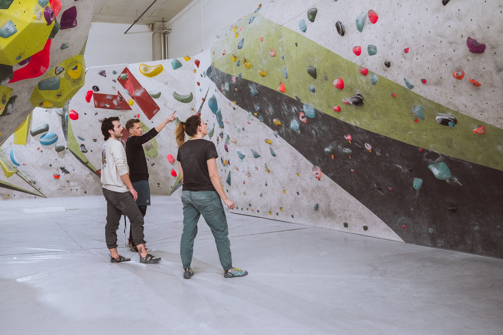 Karin, Paschi und Jeff besprechen einen Plan, wie sie beim Bouldern (Klettern) vorgehen wollen.