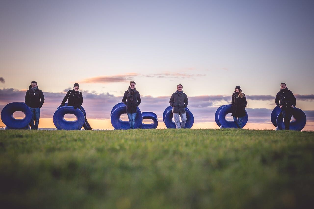 Das required Team in Kopenhagen, auf einer grünen Wiese mit dem Himmel und Sonnenuntergang im Hintergrund