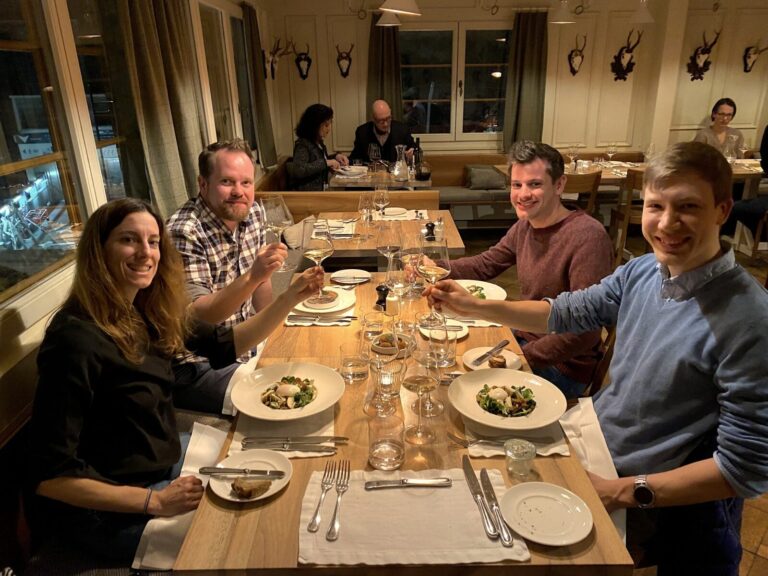 Foto vom required Team im Restaurant, alle mit einem Glas Wein beim anstossen