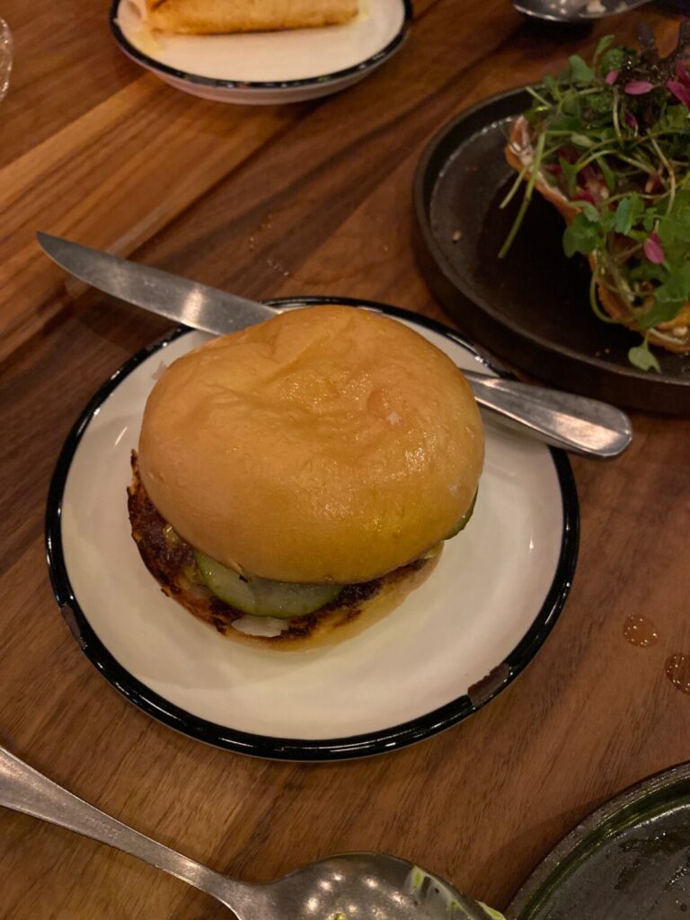 eine Schüssel mit einem Burger auf einem Teller auf einem Tisch