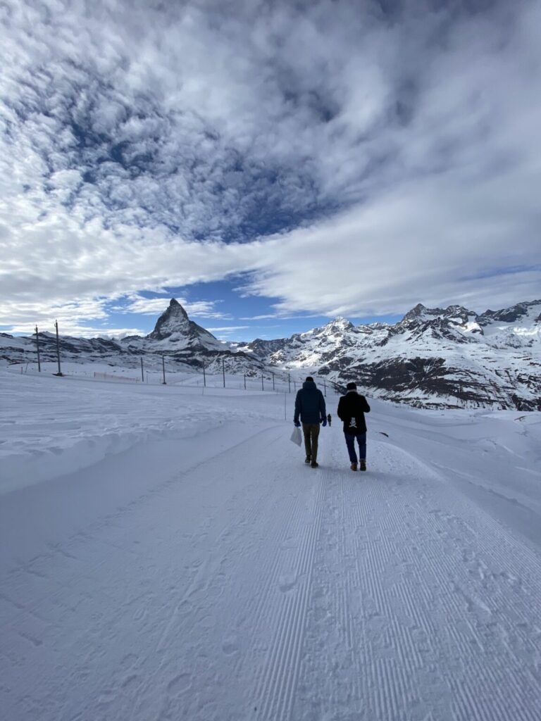 Velthy und Ulrich spazieren über den Schnee, im Hintergrund das Matterhorn.