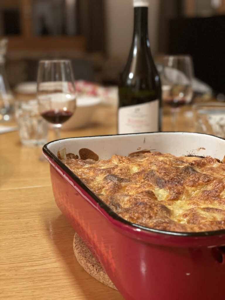 Photo of a gratin dish with vegetable lasagna and a bottle of red wine next to it