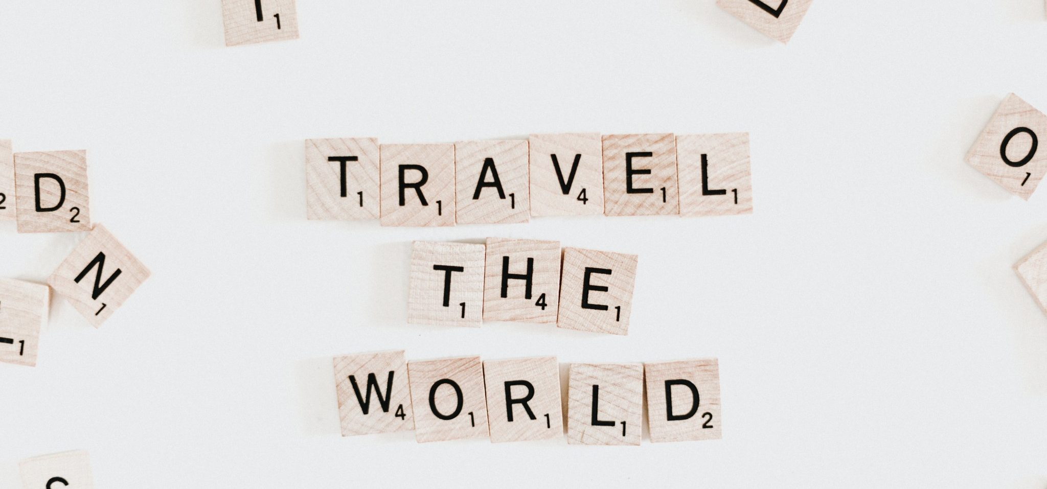 Die Worte "Travel the World" als einzelne kleine Holzstücke aus dem Spiel Scrabble