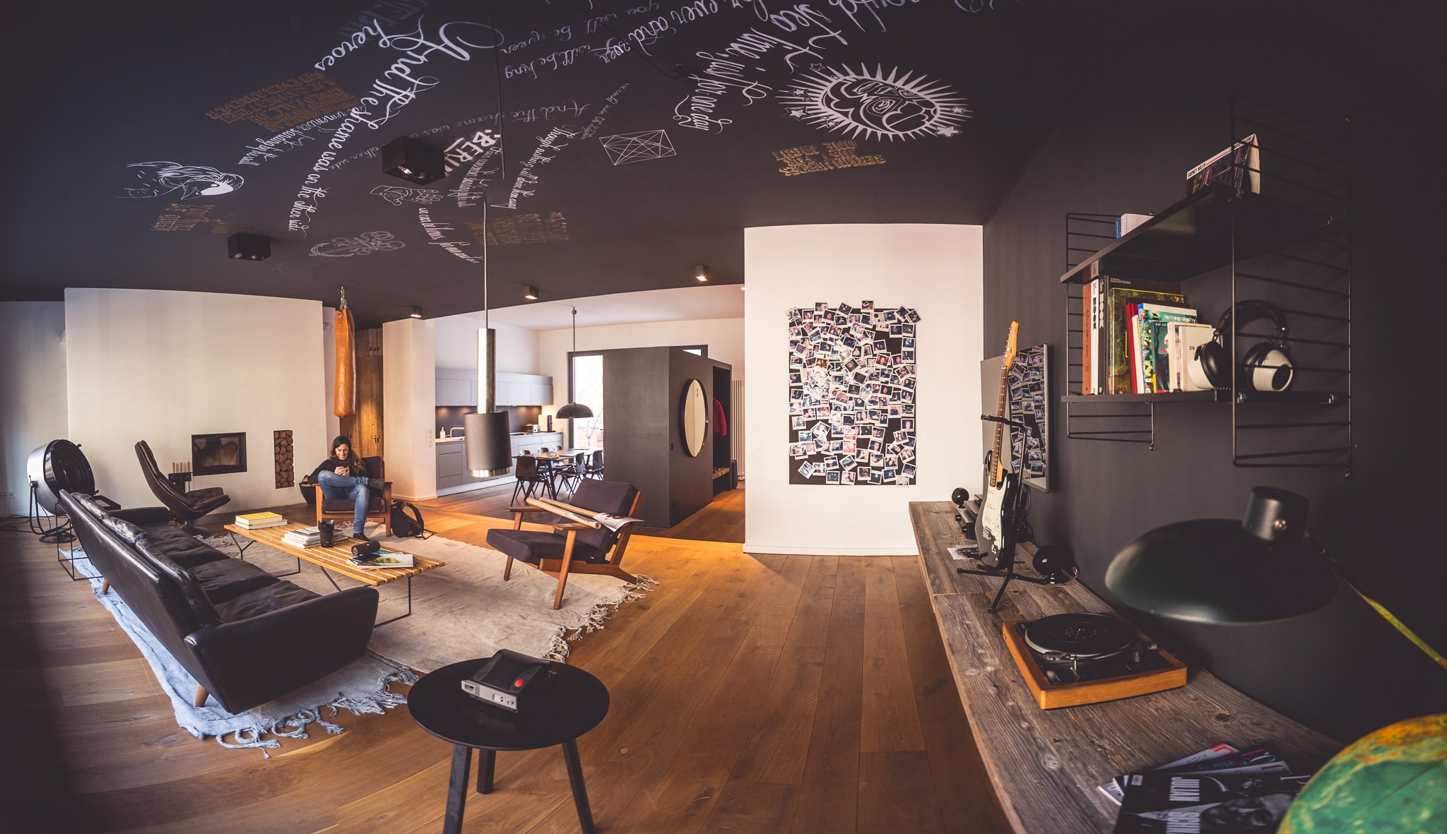 Arbeitsraum welches wie ein Wohnzimmer eingerichtet ist mit Sofa, Schallplatte, Fotowand und eine Küche