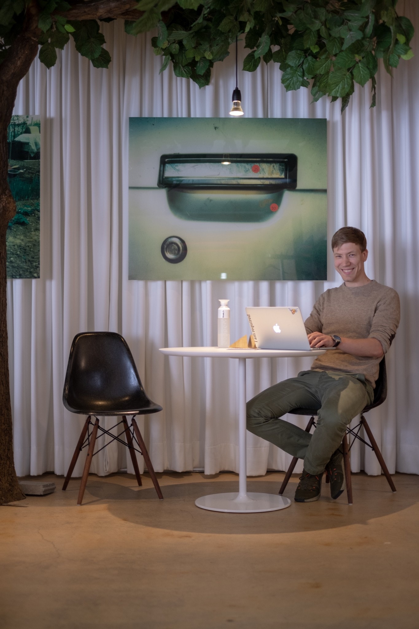 Foto von Ulrich an einem Tisch sitzend vor seinem Laptop welches den Bereich für die Besprechungen im Coworking zeigt