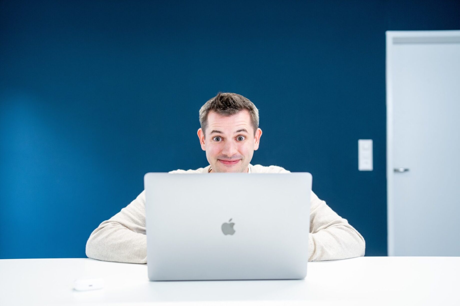 Dominik Schilling schaut mit grossen Augen hinter dem Laptop hervor