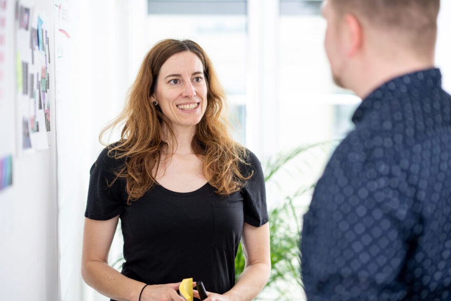 Karin standing with a client in front of a whiteboard explaining stuff in a workshop