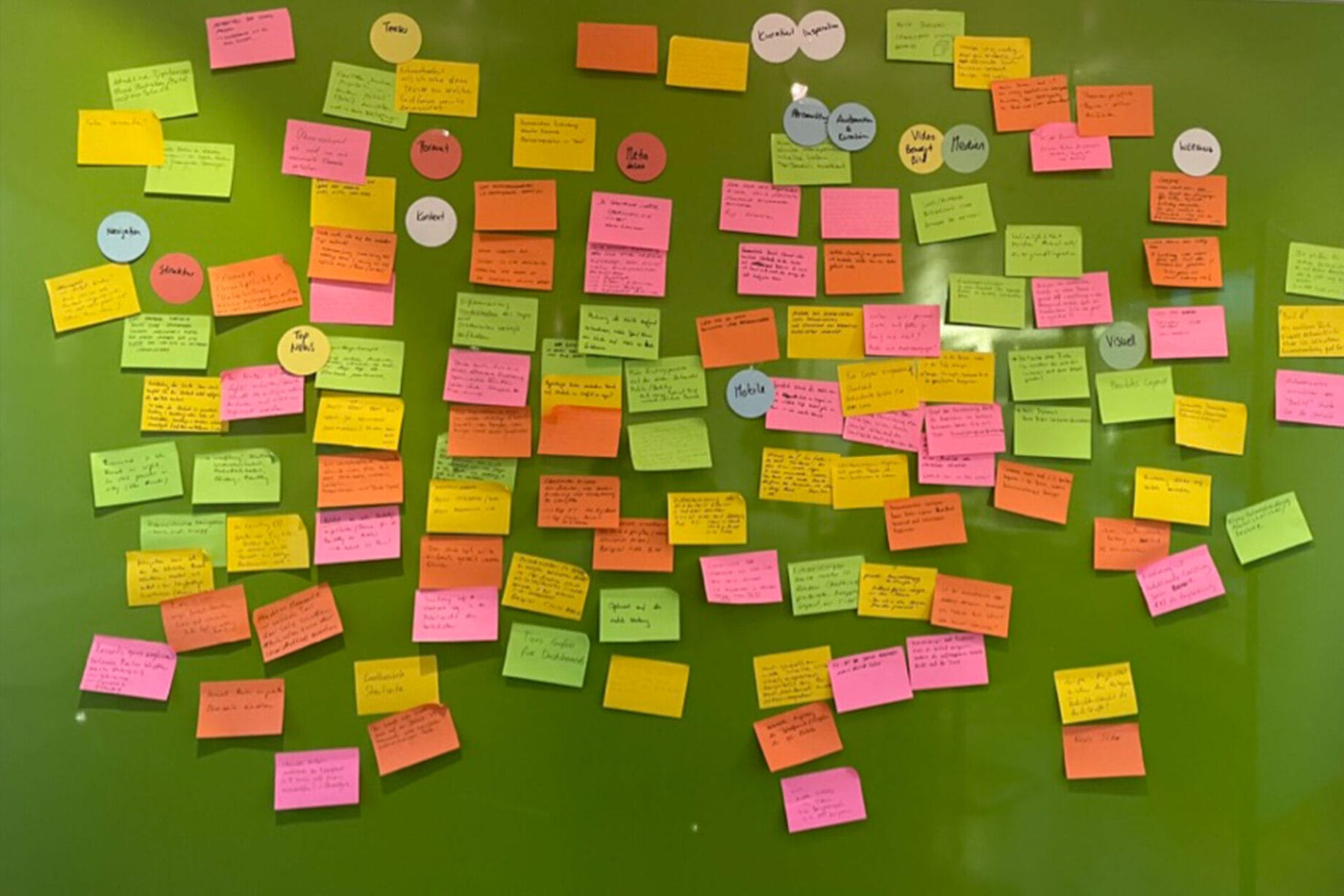 Post its on a green pin poard clustering the ideas and topics of the front-page concept