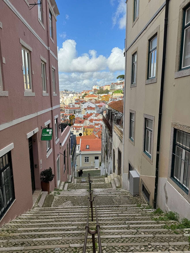 A long staircase in Lisbon, with buildings in the background, in the afternoon