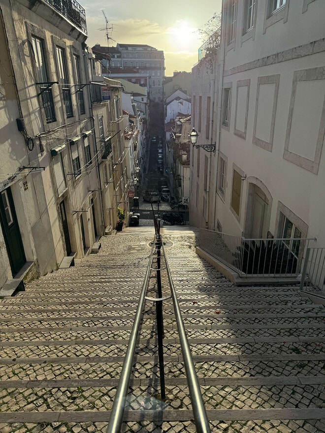 A long staircase in Lisbon, with buildings in the background, in the early morning