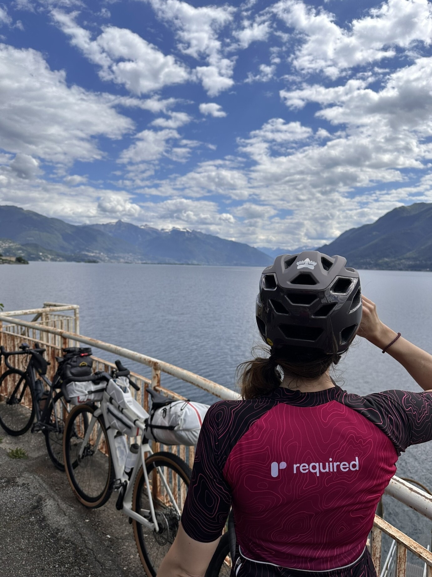 Karin photographed from behind, wearing the cycling jersey with a view of Lake Maggiore.