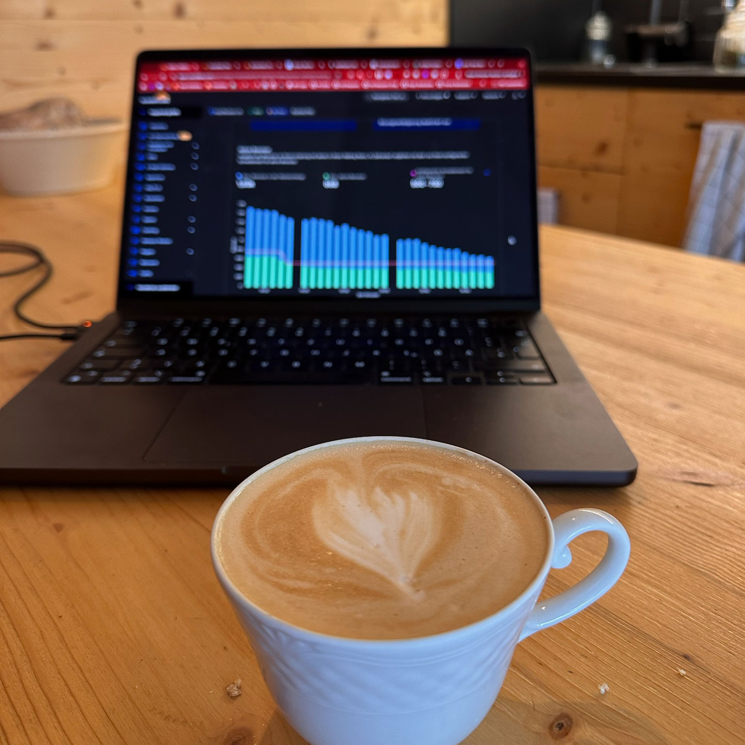 Laptop auf Tisch mit Statistik und davor ein Kaffee