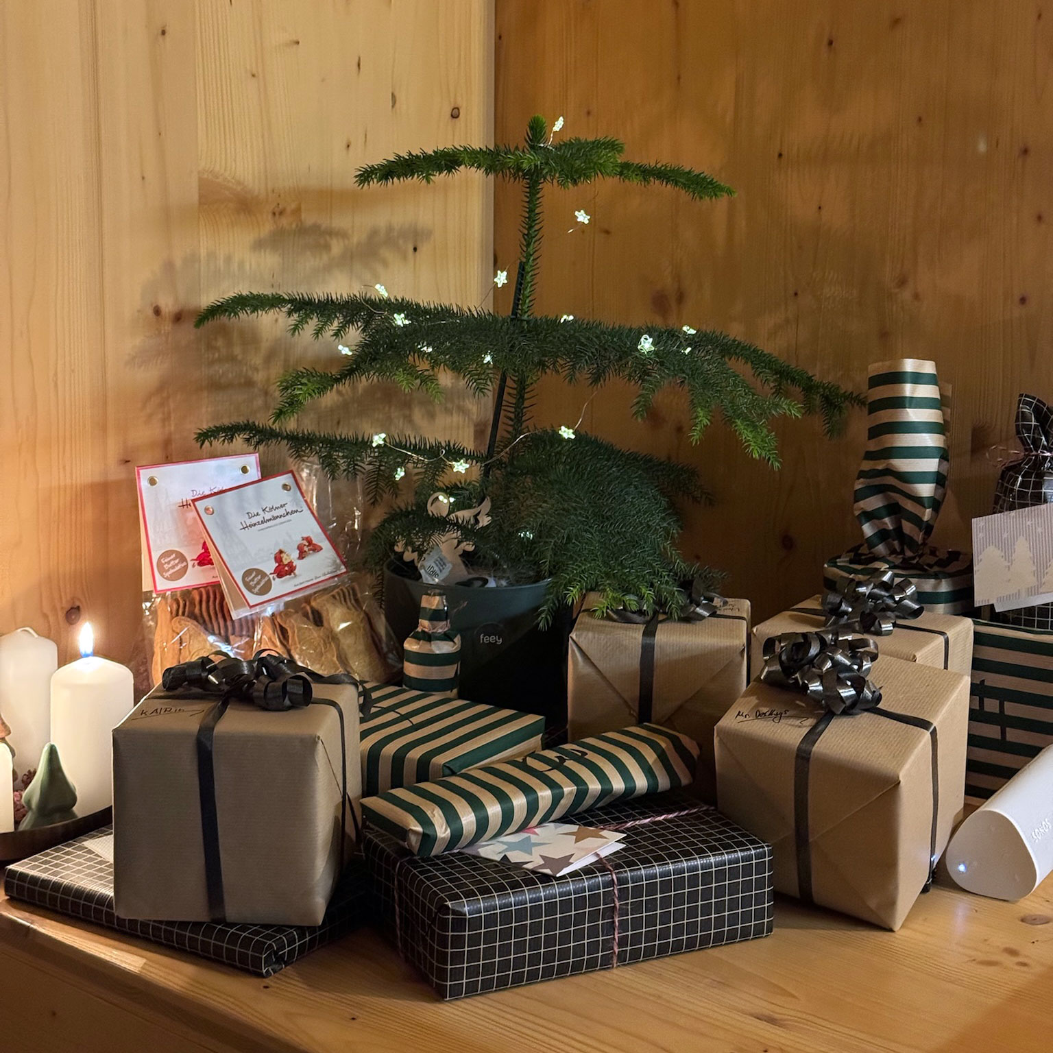 Ein kleiner Weihnachtsbaum, umgeben von schön verpackten Geschenken und stimmungsvoller Dekoration.