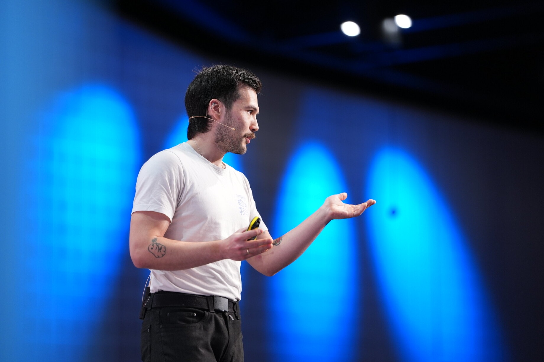 Jeff talks on stage of WordCamp Europe Basel 2025. He has a a microphone attached to his ear and gestures with his hands.