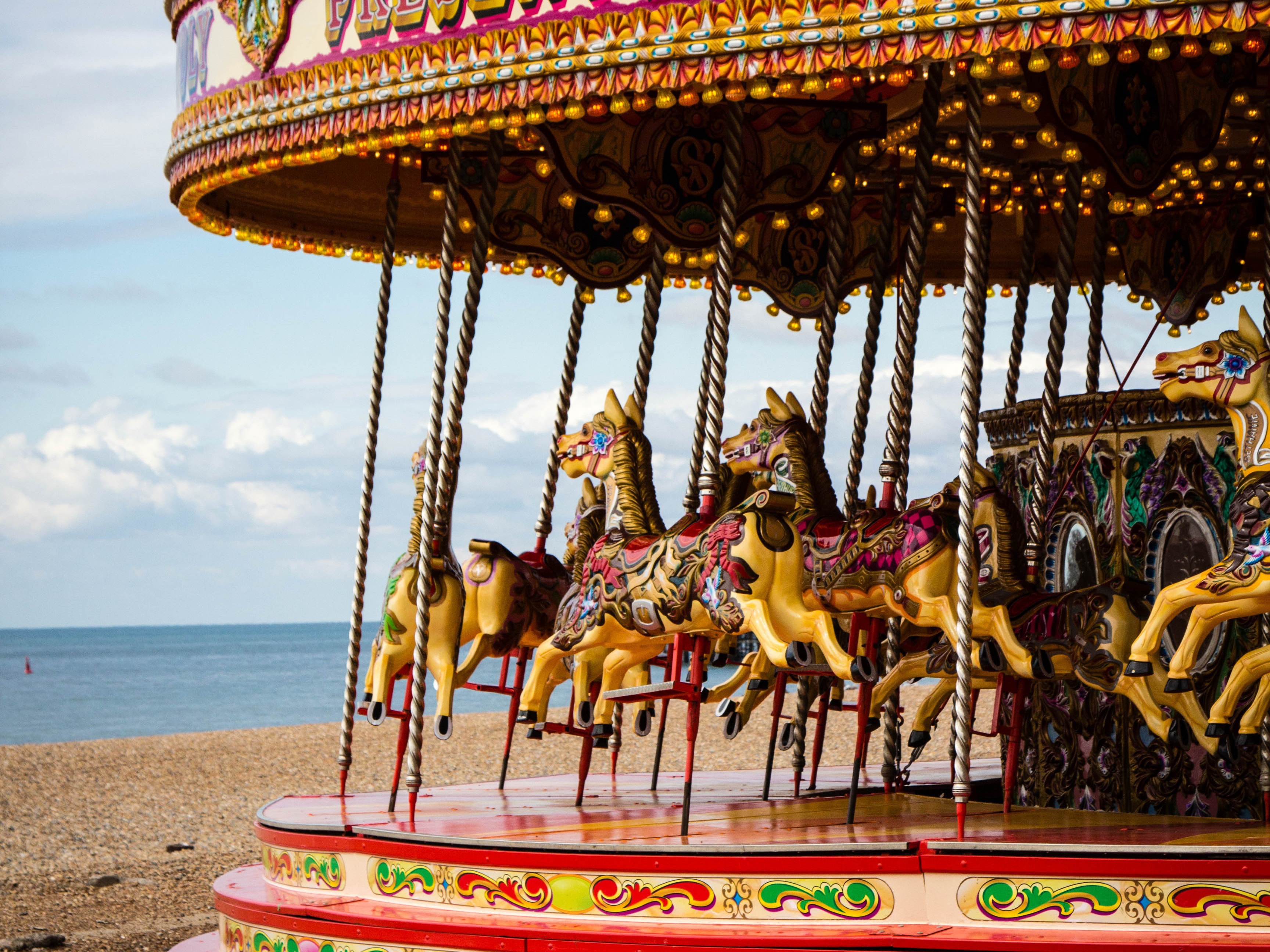 Ein Karussell mit Pferdefiguren steht am Strand.