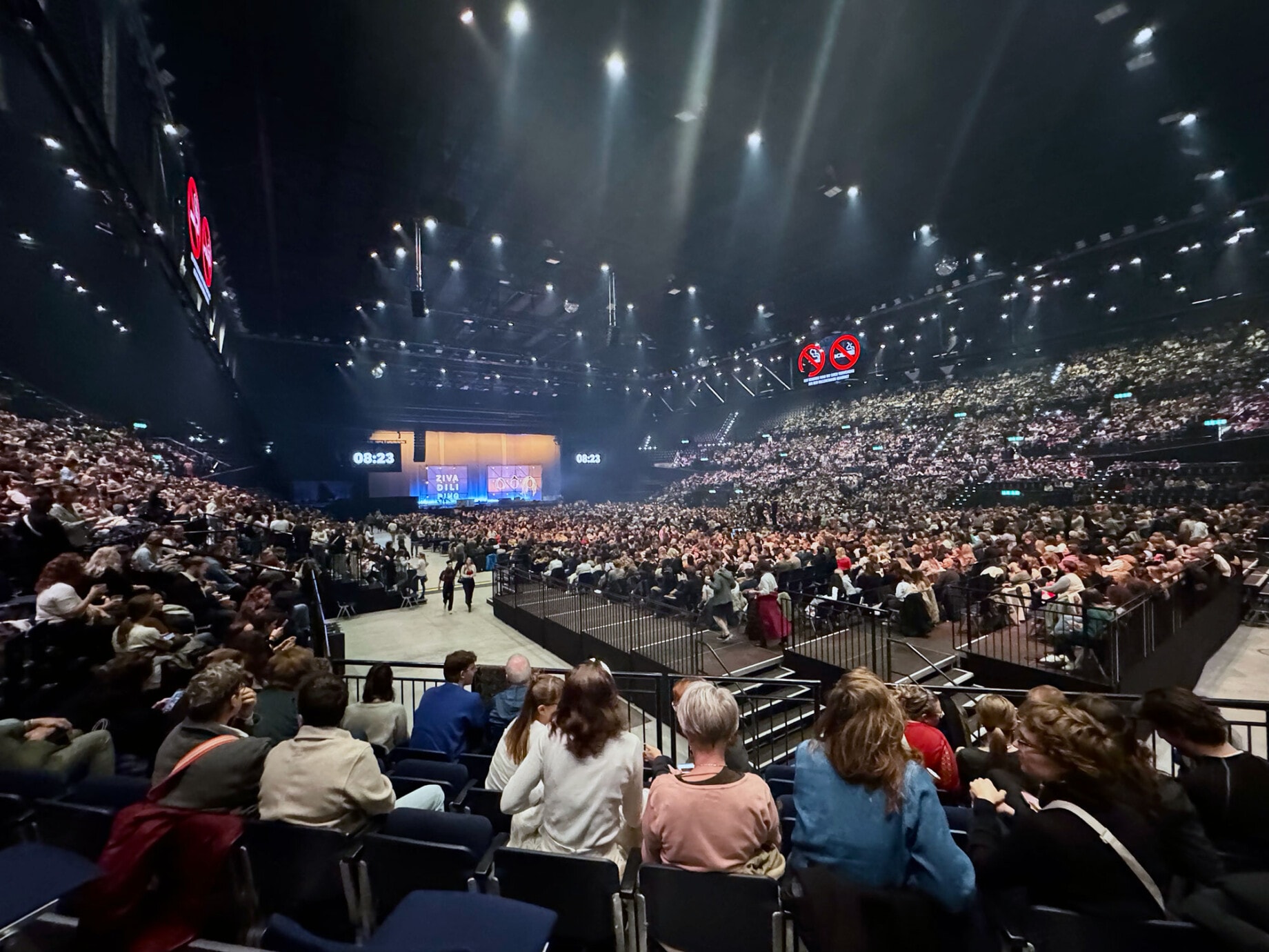 Blick in ein voll besetztes Hallenstadion während einer Veranstaltung mit Bühne, Beleuchtung und Publikum.